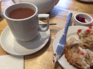 Cup of tea, scone with red jam