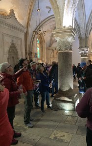 Tour guide talking to people in a room with vaulted ceiling and columns