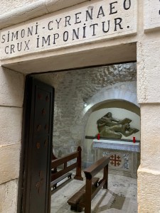 small chapel with kneeling benches and an image of Simon of Cyrene taking the cross from Jesus