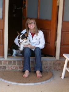 Teen girl in jeans and white fleece shirt holding black, white and tan corgi