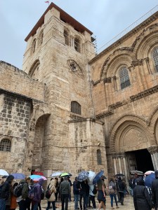 Entrance to a tan, stone church with a bell tower