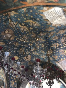 Blue ceiling covered with gold winged cherubs and gold stars with many silver chandeliers hanging down