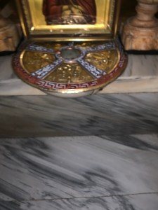 Gold disc on white marble floor that covers the stone of Golgotha