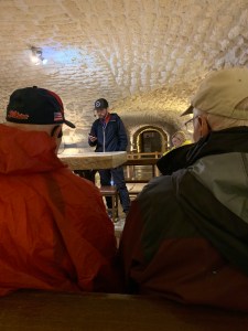 Man in cap reading in dimly lit room with low ceiling