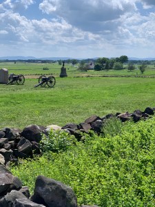 Field with low rock wall, two cannon and in the distance a statue of a soldier using his rifle as a club