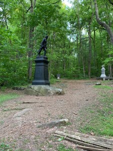 Statue of a man walking with a rifle in a clearing in the woods
